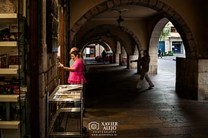 Dos personas leyendo bajo los arcos en Girona, gesto urbano de pausa y presencia.